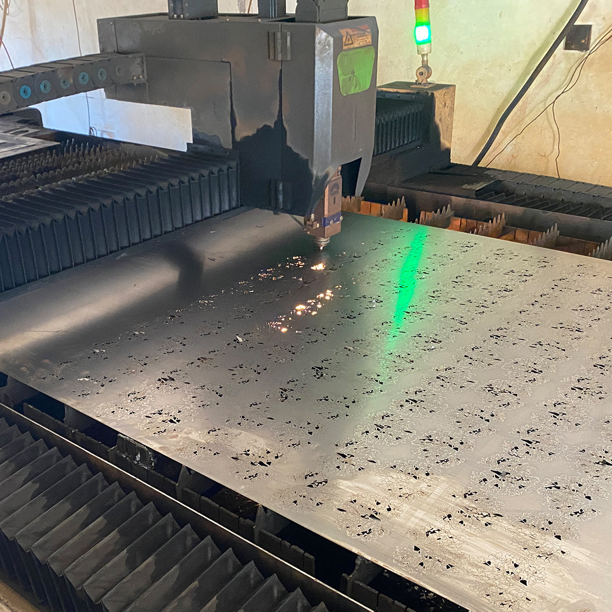 Laser cutting custom decorative designs from sheet metal with visible sparks