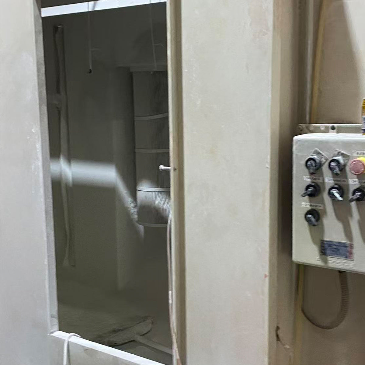 Powder coating being applied to metal parts inside a spray booth