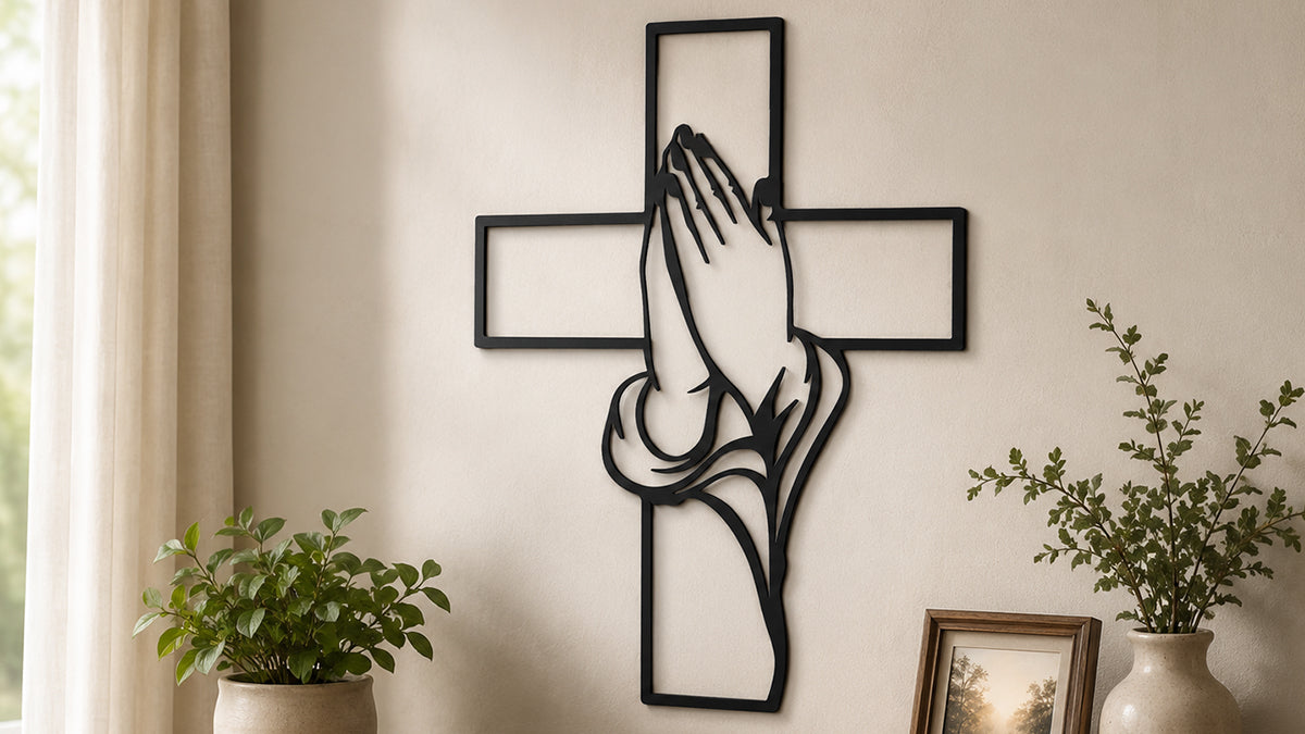Black metal praying hands cross wall decor displayed on an indoor wall