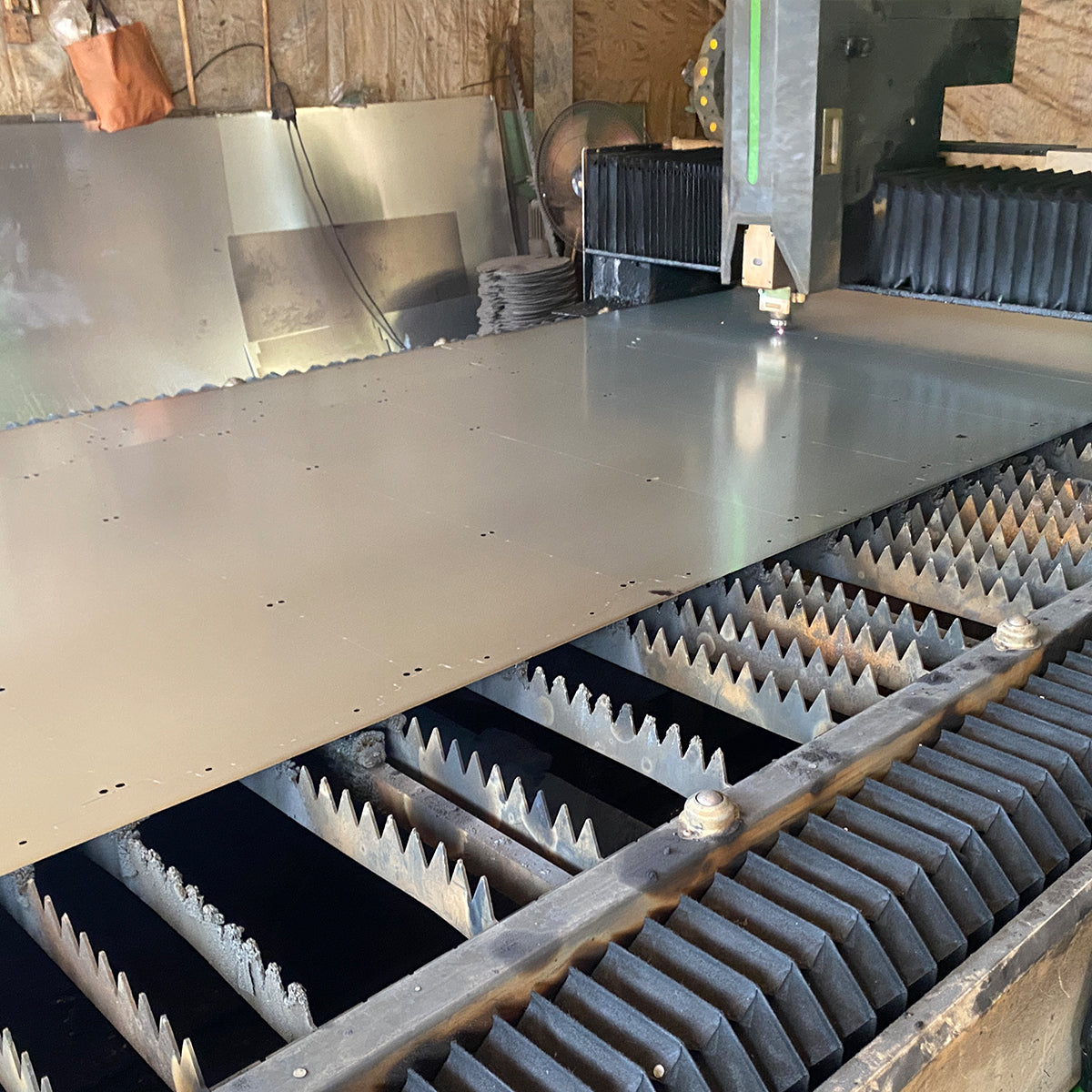 Fiber laser cutting machine processing a large sheet metal panel in our workshop