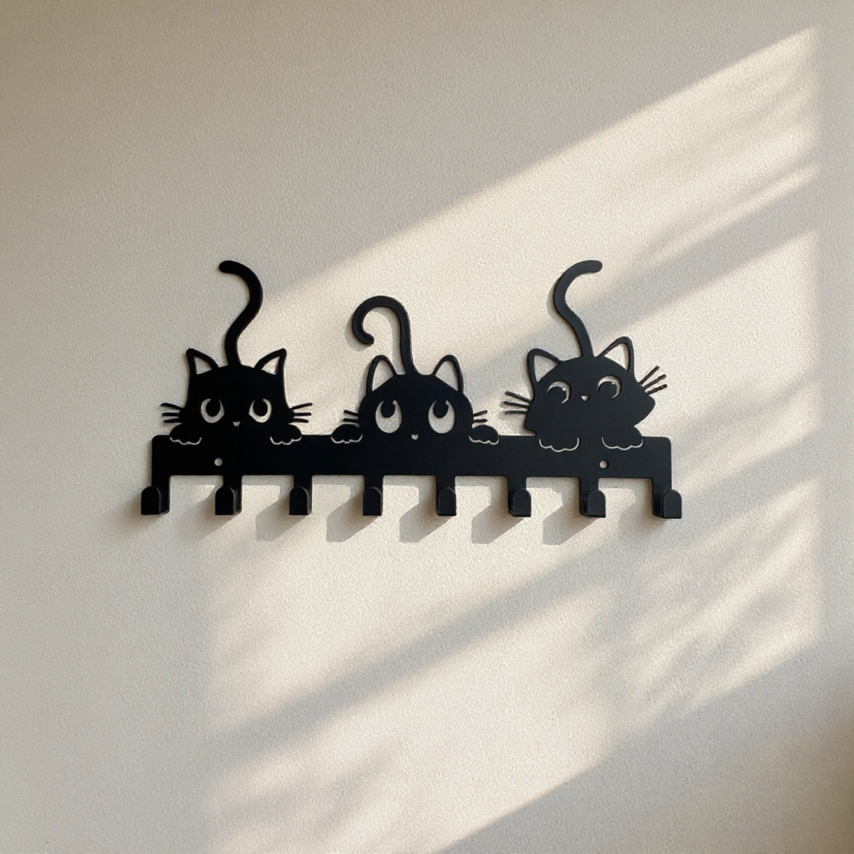 Black metal wall hook rack with three playful cat silhouettes and multiple hooks