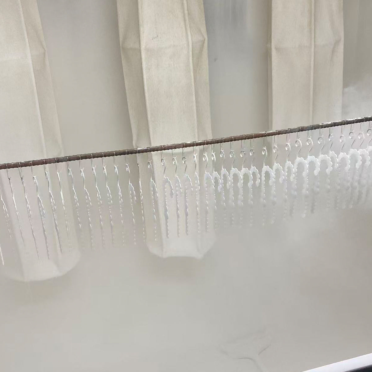 Batch of small white powder-coated metal parts hanging on a production line